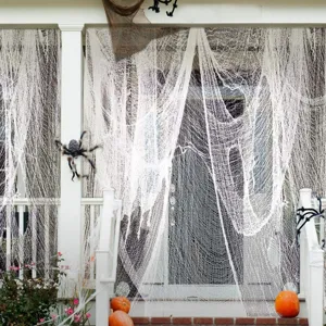 Halloween creepy cloth detail showing white mesh hanging on porch with spider and pumpkins.