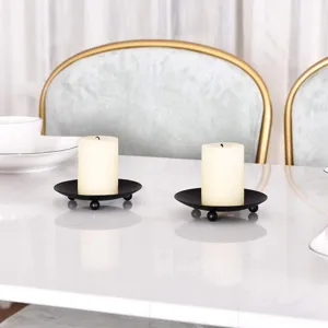 Portavelas de hierro negro con velas de pilar blancas, detalle de decoración de mesa.