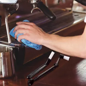 Detailed view of the espresso machine cleaning brush with nylon bristles and spoon, bar scene.
