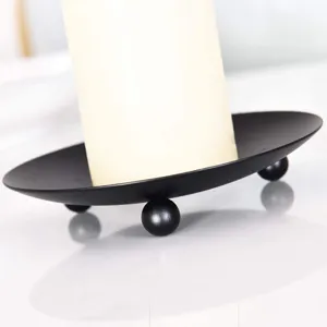 Detalle en primer plano de la bandeja portavelas de metal negro con patas esféricas.