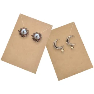 Squisiti orecchini di perle girasole e luna stella esposti su cartoncini di carta kraft marrone.