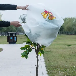 White non-woven plant protection cover with Christmas bell print for winter frost and pest control.