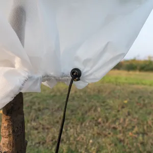 White non-woven plant cover detail showcasing drawstring and toggle for frost and insect protection.