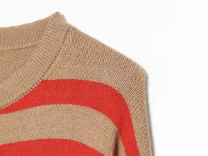Primo piano dettagliato del maglione lavorato a maglia da donna a righe beige e rosso.