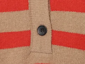 Vista dettagliata di maglia a righe rosse e cachi da donna con bottone scuro.
