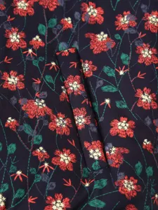 Floral printed padded coat fabric detail close-up showing vibrant red flowers and green leaves.