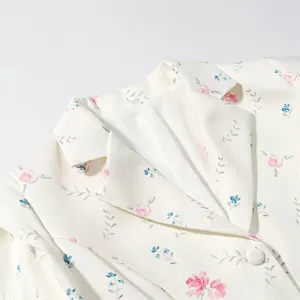 Close-up detail of a white floral blazer jacket with notch lapel and single button.