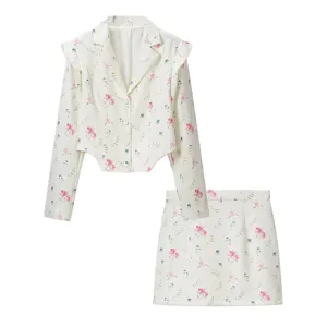 Detail shot of the floral blazer and skirt set, white fabric with pink and blue prints.