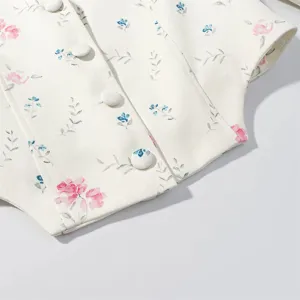 Close-up detail shot of women's floral vest featuring delicate fabric buttons and print.