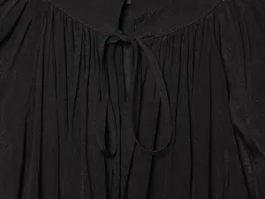 Close-up detail van de elegante zwarte geplooide damesblouse kraag met modieuze strikervaring.