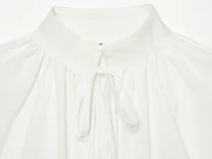 Close-up van de elegante witte damesblousekraag met strikdetail en maatlabel.