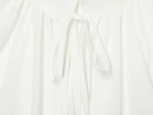 Close-up detail van de halslijn van een witte damesblouse met strikbandjes en fijne plooien.