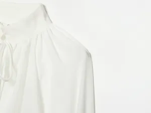 Witte dames langeweg blouse detail weergave, elegante opstaande kraag met fijne plooien.