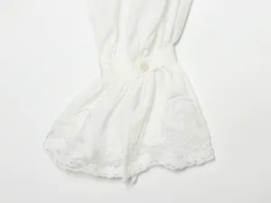 Detailopname van de witte blousemouw met fijn kantaccent en een enkele knoopsluiting.