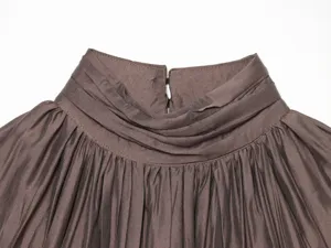 Close-up detail view of the elegant pleated high stand collar on a chic brown women shirt.