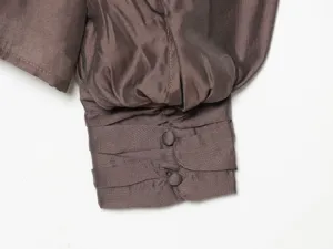 Brown silk-like blouse sleeve detail, elegant button cuffs and pleated design for women.