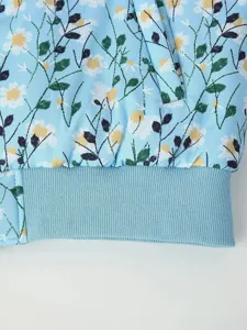 Women floral printed padded jacket detail showing blue daisy pattern and ribbed hem.