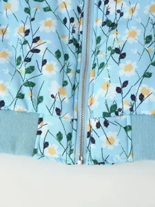 Close-up detail of women light blue floral print padded jacket with metal zipper hem.
