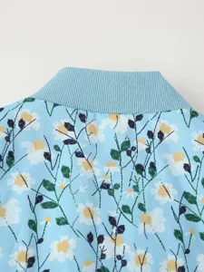 Close up view of women floral printed padded jacket collar, blue fabric with white daisy details.