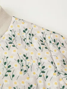 Detail shot of floral print quilted jacket shoulder showing white daisies on beige fabric.