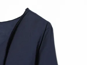 Λεπτομέρεια εξωτερικού ενδύματος μακρυμάνικου μπλε σκούρου με μινιμαλιστικό σχεδιασμό.