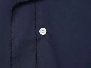 Λεπτομερής κοντινή λήψη σκούρου μπλε υφάσματος με κούμπωμα με κουμπί και καθαρές ραφές