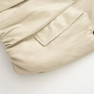 Primo piano della morbida giacca in pelle beige con tasca elegante e cuciture fini.