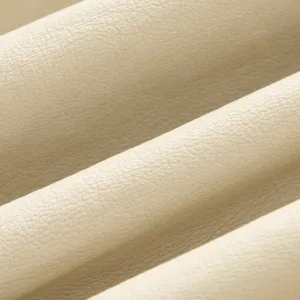 Primo piano del materiale in ecopelle beige, vista dettagliata della texture liscia per abbigliamento moda.