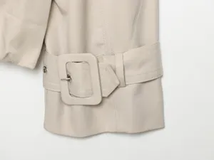 Close up detail of women trench coat sleeve with matching fabric belt buckle and metal eyelet.