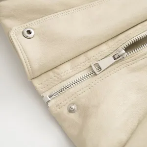 Primo piano dettagliato di una giacca in pelle beige da donna con zip e bottoni.