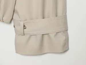 Detailed close-up of women trench coat sleeve cuff featuring a stylish belt and metal eyelets.