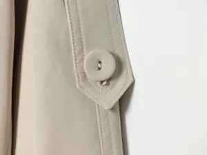 Close-up detail view of women's stylish trench coat featuring a button tab and fine stitching.