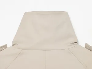 Detailed close-up of women's beige trench coat high collar and shoulder details.