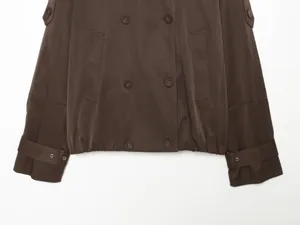 Brown double-breasted short trench coat jacket detail, featuring buttons and side pockets.