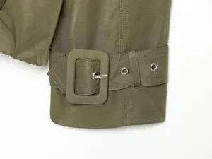 Olive green trench coat sleeve cuff detail with matching fabric buckle and metal eyelets close-up