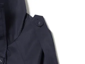 Close-up detail of navy blue women short trench coat shoulder epaulet and button.
