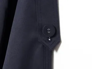 Close up detail of women solid navy blue trench coat button strap stylish winter apparel.