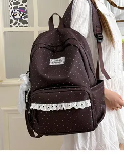 Details of the dark brown polka dot backpack featuring cute white lace ruffles and bow.
