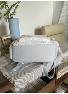 Detail view of light blue checkered and polka dot backpack, showing bottom and straps.
