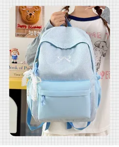 Vue détaillée du joli sac à dos d'école à carreaux bleus avec broderie nœud et pendentif.