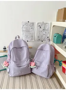 Light purple minimalist backpack detail featuring cute tulip pendant and clover embroidery.