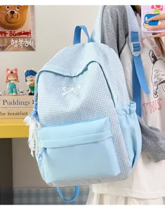 Vue détaillée du sac à dos à carreaux bleu clair avec nœud blanc et pendentif en dentelle.