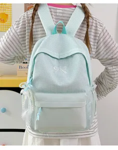 Vue détaillée du sac à dos à carreaux vert clair avec broderie nœud et perles délicates.
