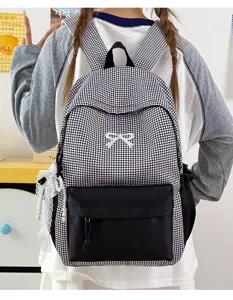 Détails du sac à dos à carreaux noir et blanc avec nœud mignon et pendentif en dentelle.