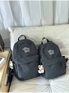 Detailed view of the Korean style plaid canvas backpack with front pocket and cute charm.