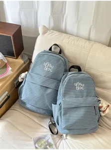 Detail view of stylish blue plaid backpack featuring cute pendants and roomy front pocket.