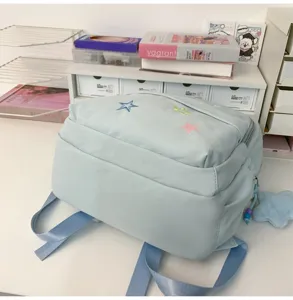 Light blue school backpack detail view featuring colorful embroidered stars and cute design.