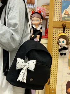 Minimalist black mini backpack featuring a cute polka dot bow pendant for stylish daily wear.