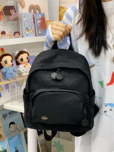 Mini black nylon backpack detail view, with front zip pocket and cute design for daily use.