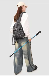 Vue détaillée d'un mini sac à dos noir à pois avec bâton de randonnée en plein air.